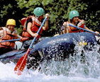 People paddling a raft on the white water rapids of the river.