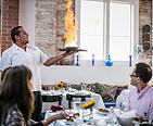 Waiter serving an entre to a table of guests that is on fire.