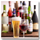 Glasses of beer and wine with bottles in the background