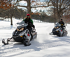 Two people riding snowmobiles